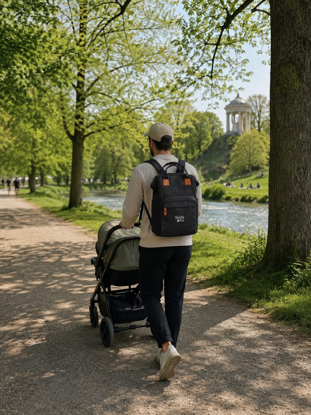 Elternteil mit Stella Bag Wickelrucksack und Kinderwagen im Park